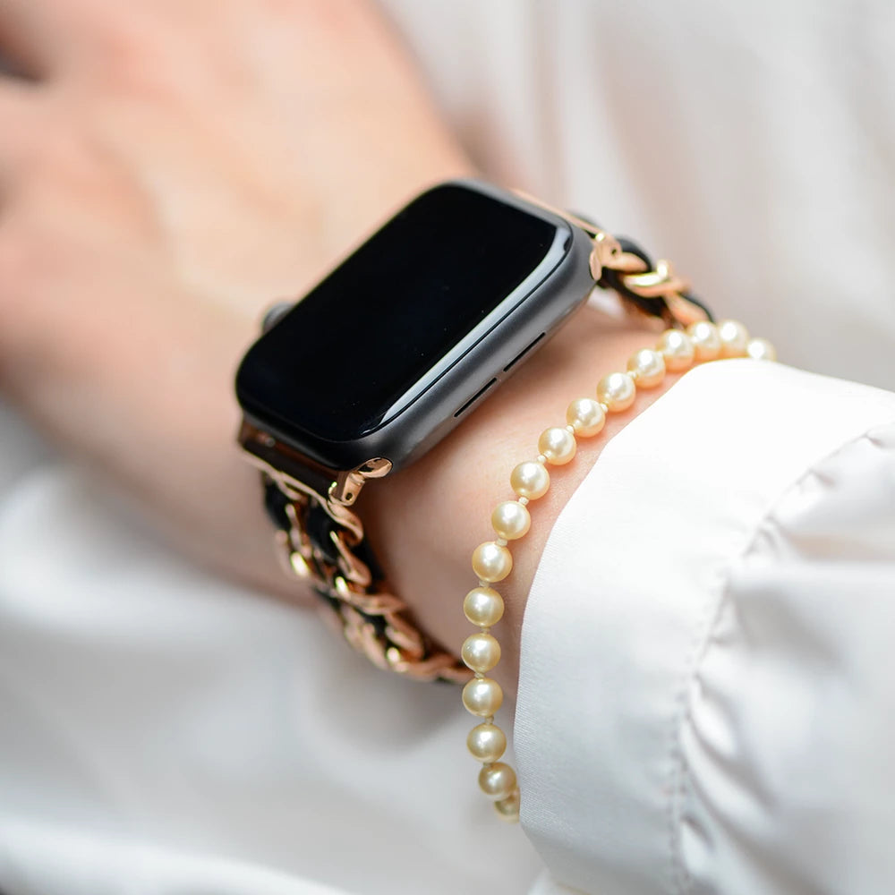 Apple Watch Kettenarmband aus Metall, Hochglanzkette und Leder, Farbe Rose Gold und Schwarz, Glamour und Luxus Style, Modell: Modena, Ansicht am Handgelenk einer Dame mit weißer Bluse und Perlenarmkette - MONTENY