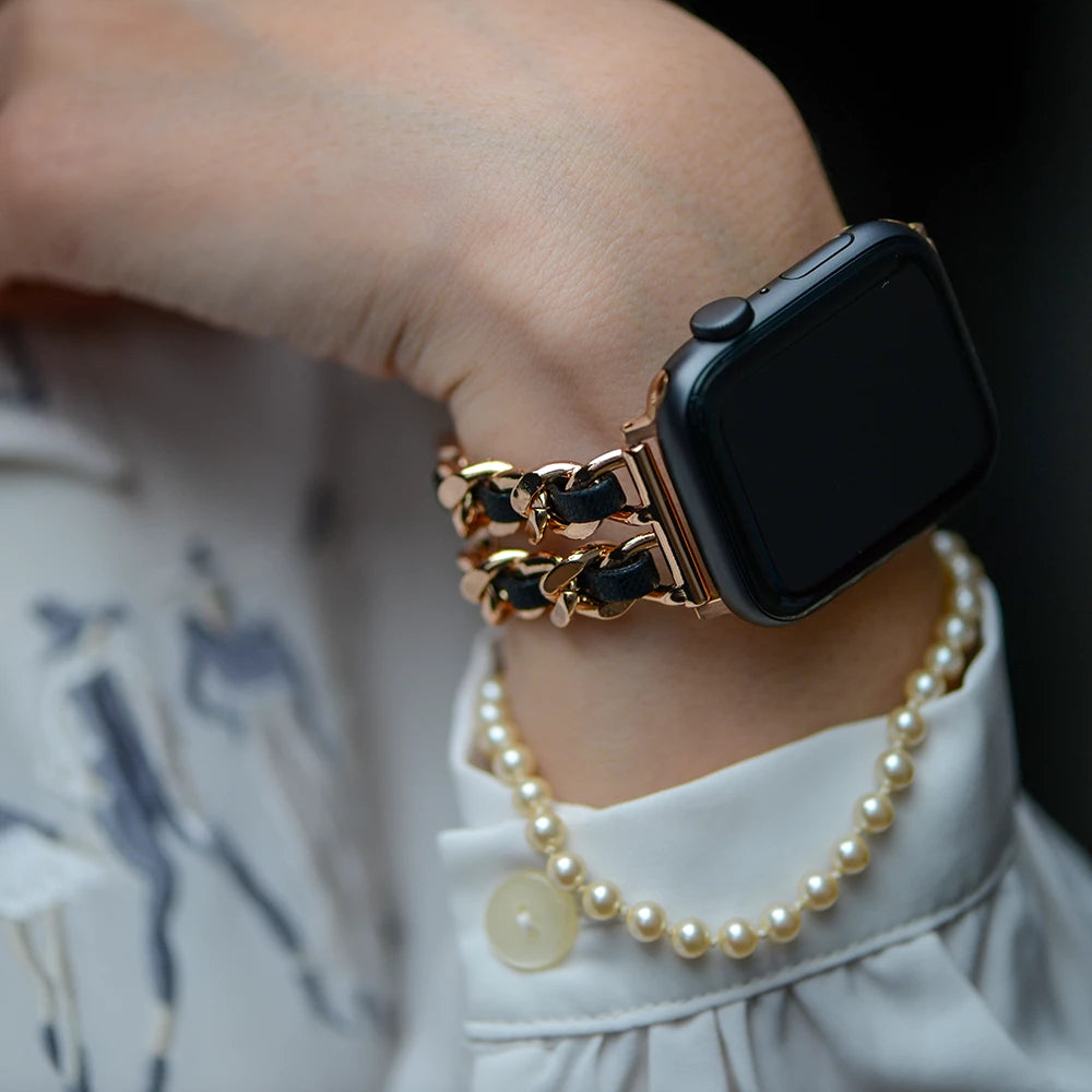 Apple Watch Kettenarmband aus Metall, Hochglanzkette und Leder, Farbe Rose Gold und Schwarz, Glamour und Luxus Style, Modell: Modena, Ansicht am Handgelenk einer Dame mit weißer Bluse und Perlenarmkette - MONTENY